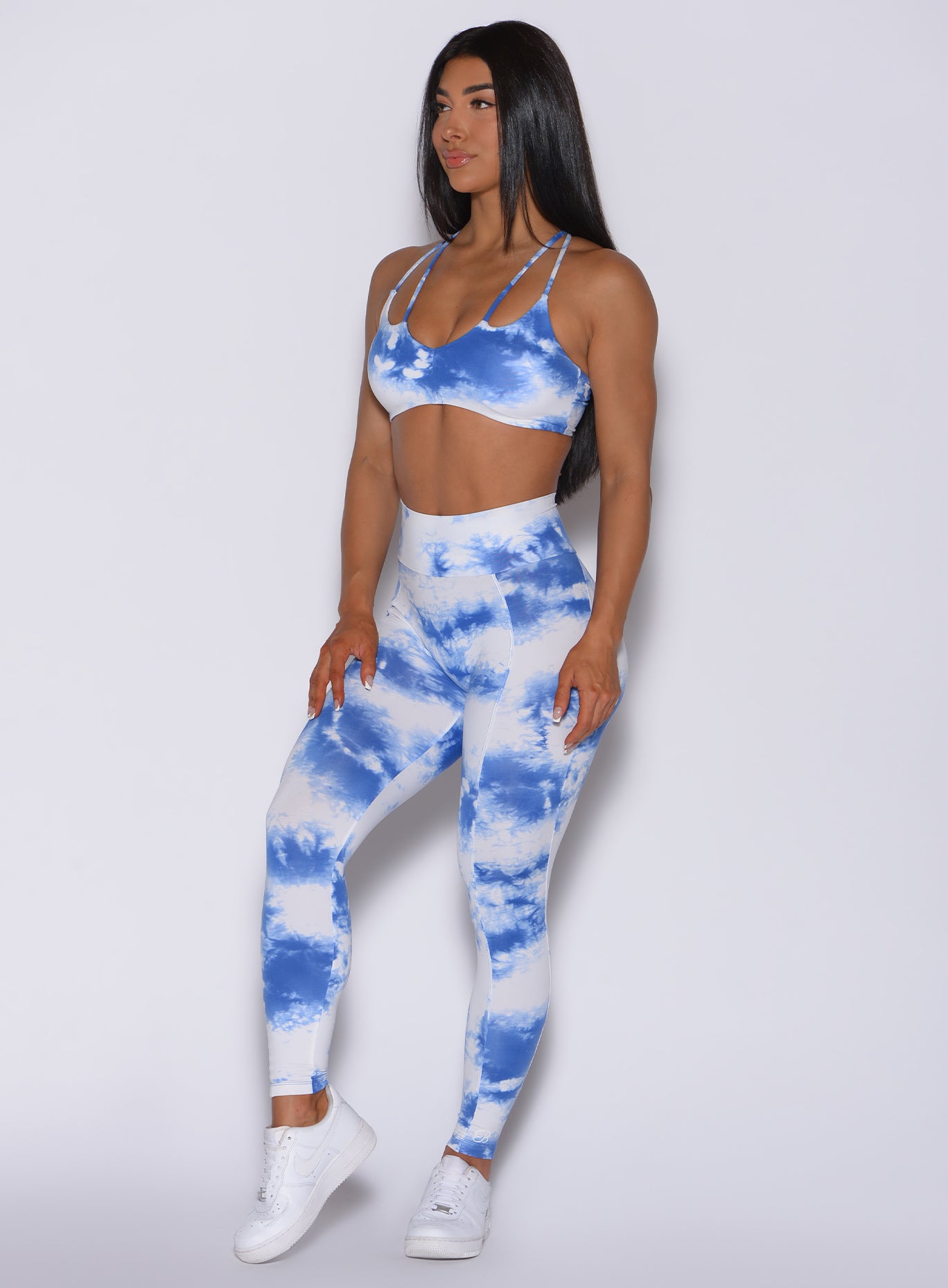 Front profile view of a beautiful model wearing our tie dye peach booty leggings in blue white and a matching bra