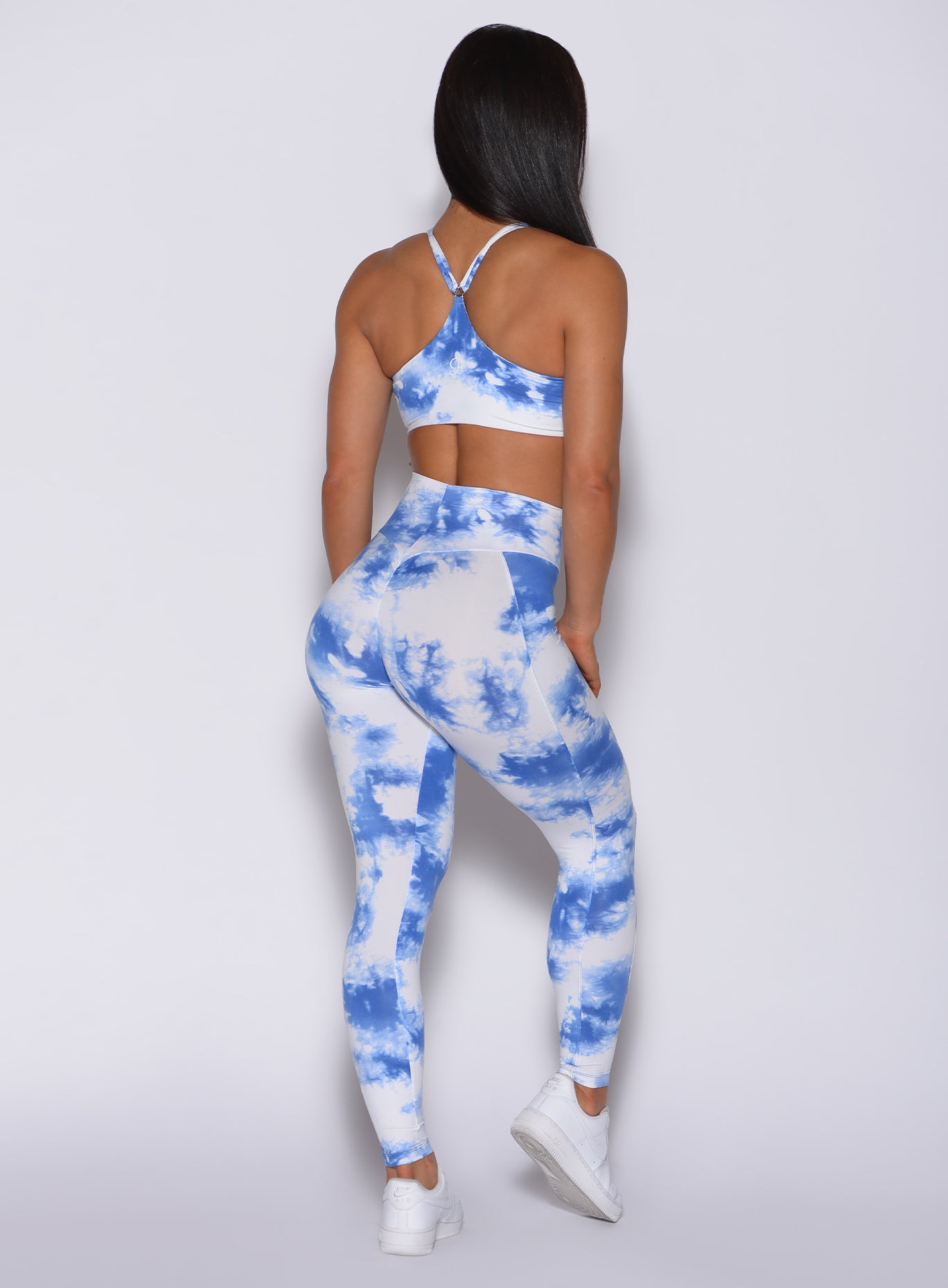 Back profile view of a model wearing our tie dye peach booty leggings in blue white and a matching bra