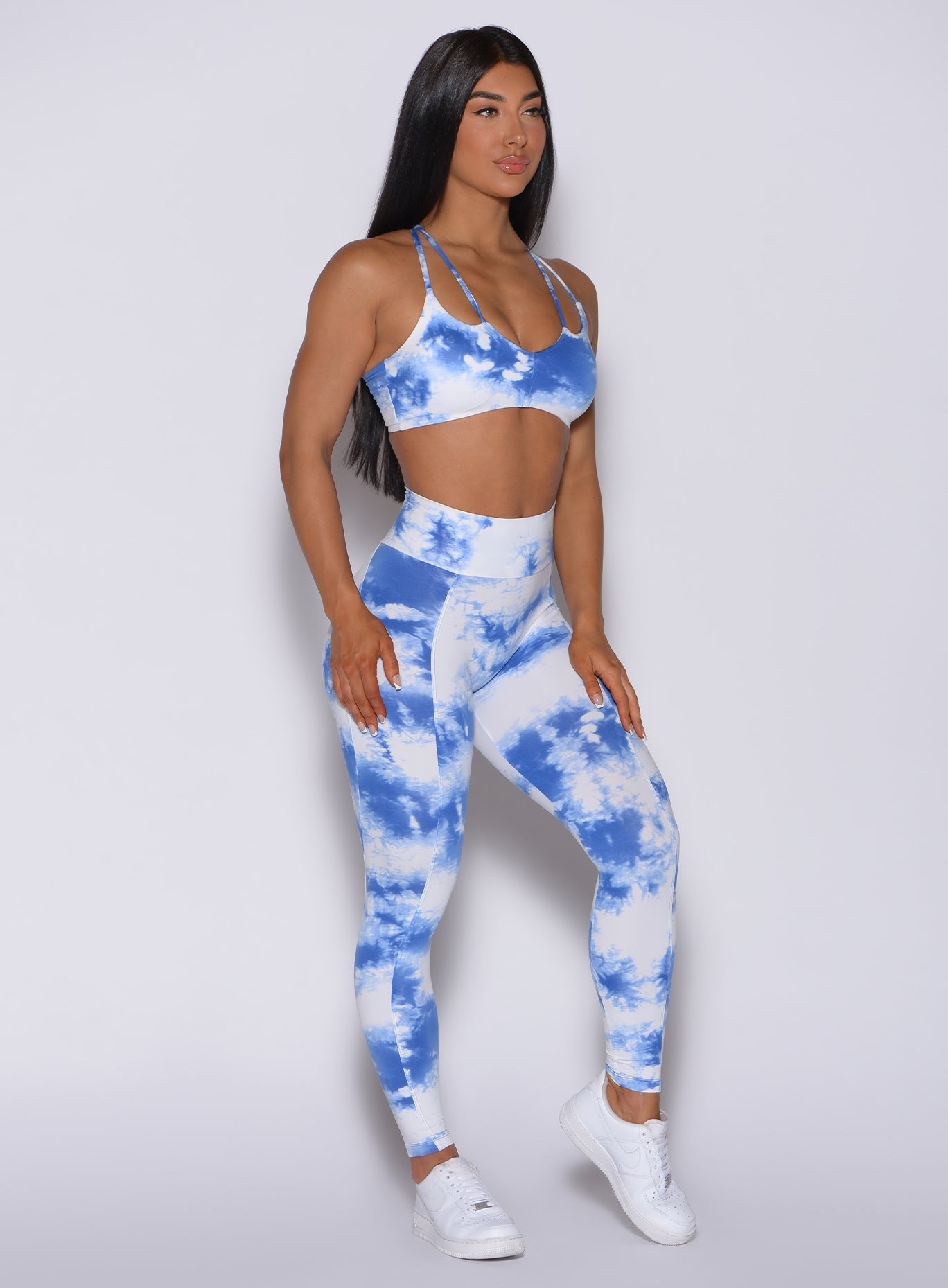 Right side profile view of a model angled slightly to her right wearing our tie dye peach booty leggings in blue white and a matching bra