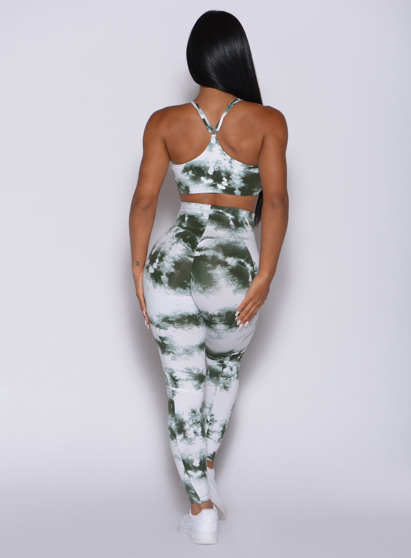 Back profile view of a model in our tie dye peach booty leggings in green white and a matching bra
