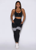 Front profile view of a model wearing our black perform thigh high leggings and a matching bralette 