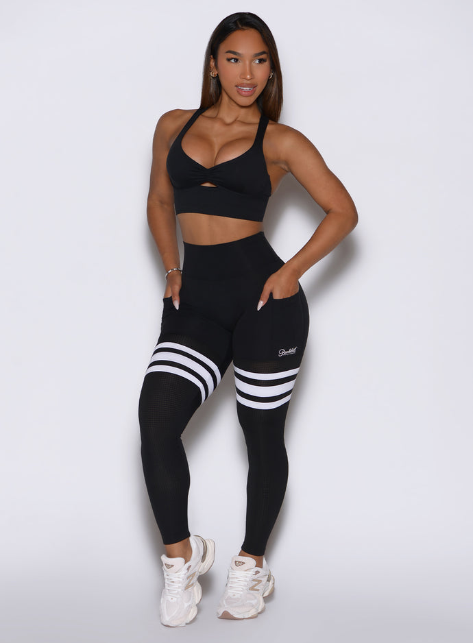 left side profile view of the model wearing our black perform thigh high leggings and a matching bralette 