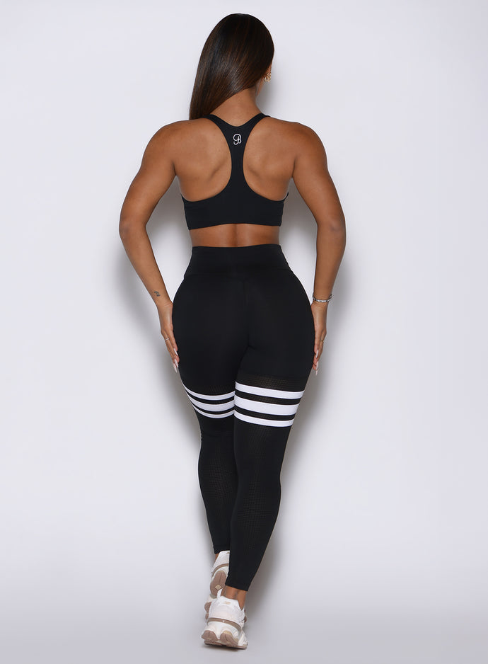Back profile view of a model wearing our  black perform thigh high leggings and a matching top 