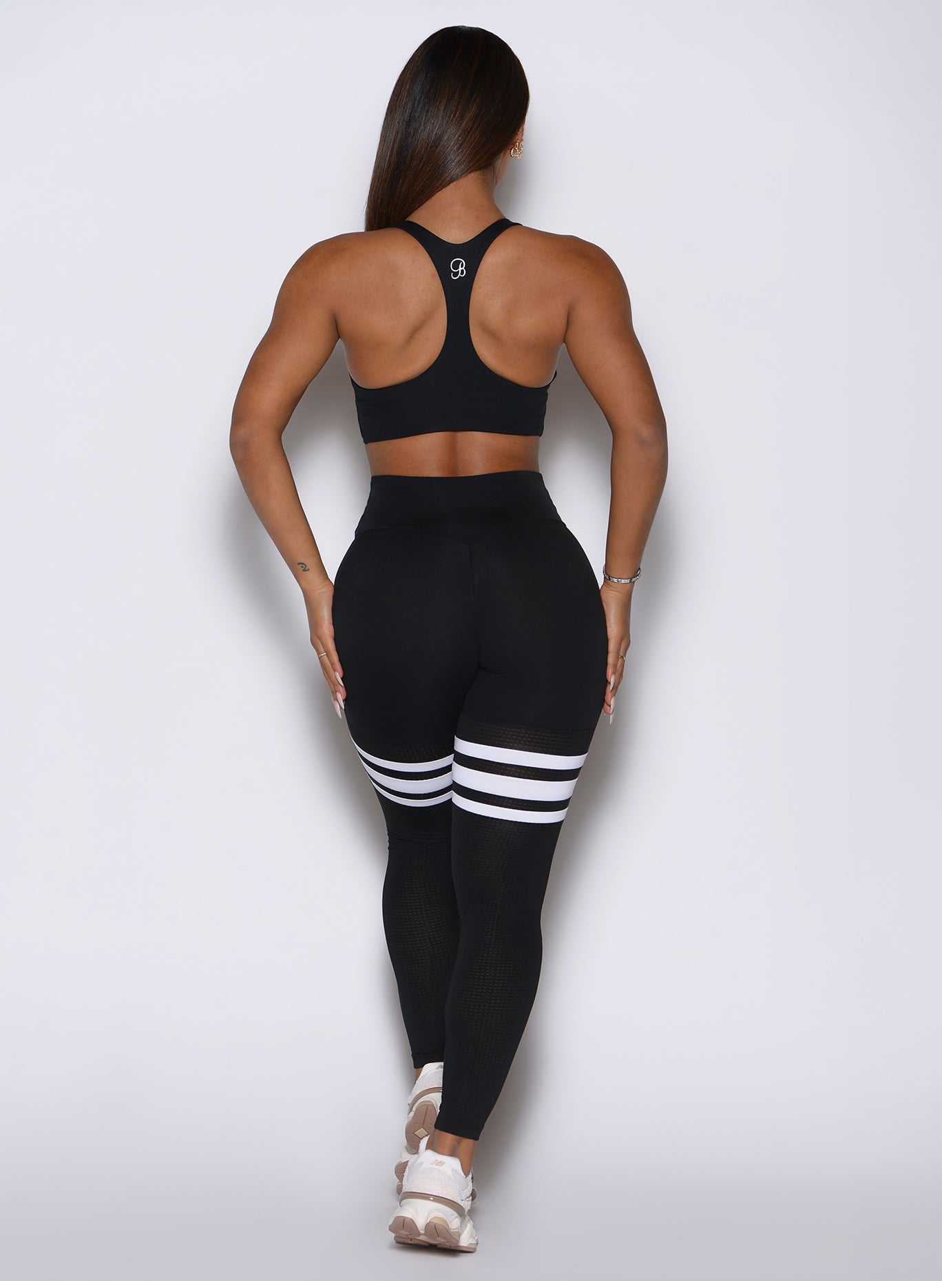 Back profile view of a model wearing our  black perform thigh high leggings and a matching top 