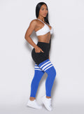 Right side profile view of a model wearing the Perform Thigh Highs in Black Sky color along with a white sports bra