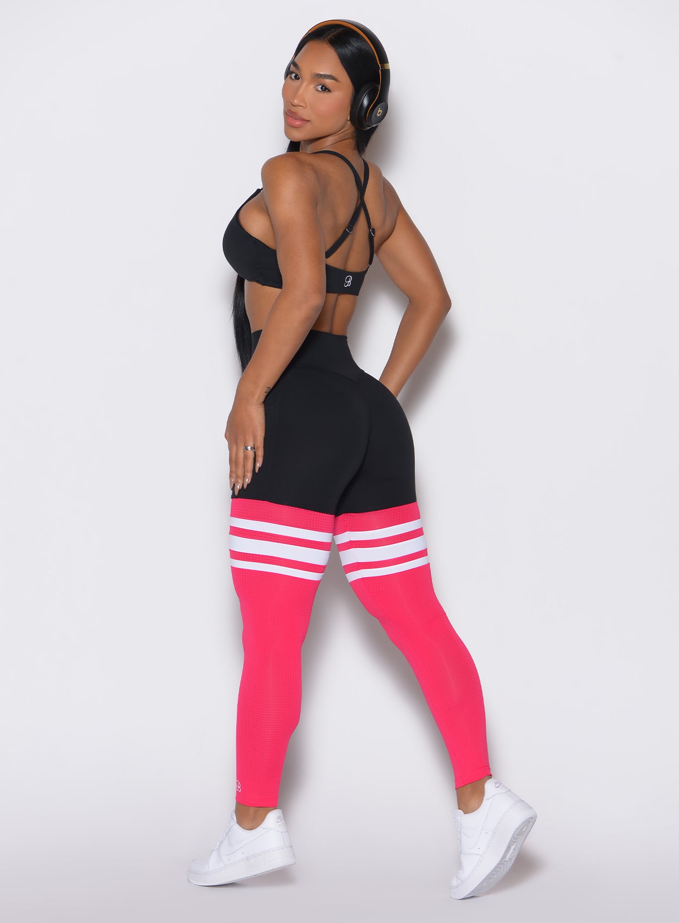 Back left side profile view of a model wearing the Perform Thigh Highs in Black Sky color along with a black sports bra
