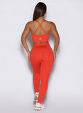 Back profile view of the model wearing our Physique leggings in Inferno color, paired with the matching top.