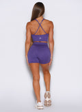 Back profile view of the model wearing our Physique shorts in Iris color, paired with a matching top.