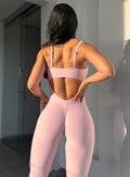 back profile view of a model in outdoors wearing the flawless form bodysuit in pink paloma color