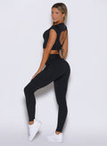 left side profile view of a model looking over her shoulder wearing the PocketBoost Leggings in Black color