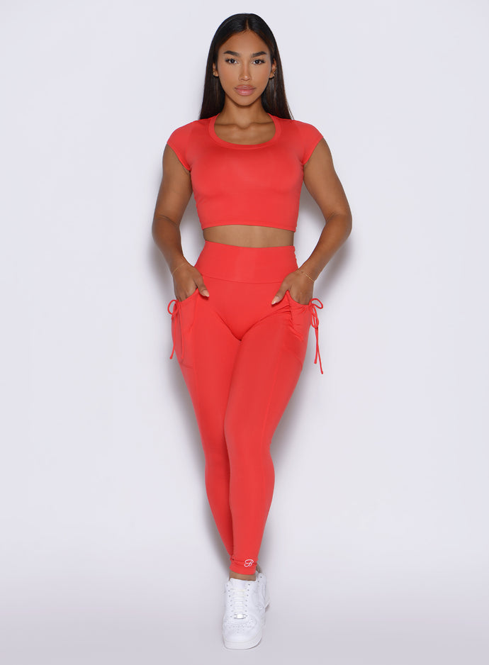 front profile view of a model with both hands in the side pockets wearing the PocketBoost Leggings in Command red color