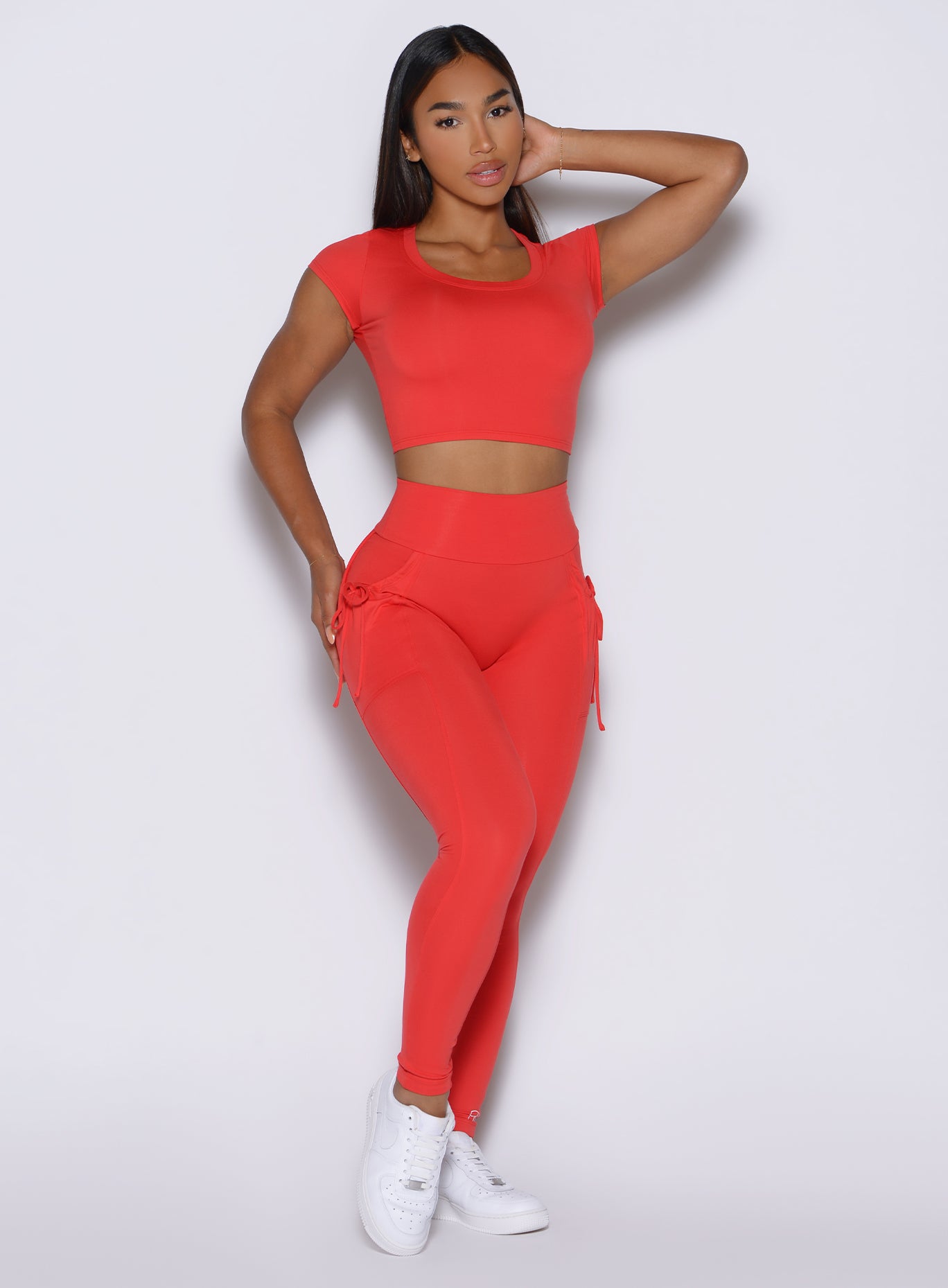 front profile view of a model wearing the PocketBoost Leggings in Command red color paired with the matching tee