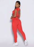 left side profile view of a model looking over her shoulder wearing the PocketBoost Leggings in Command red color