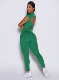 left side profile view of a model looking over her shoulder wearing the PocketBoost Leggings in Field Green color