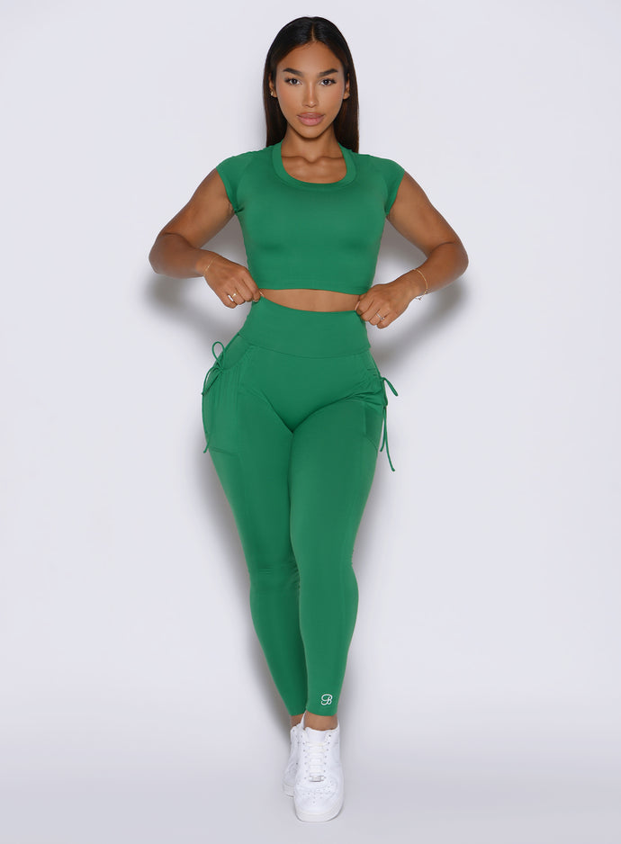 front profile view of a model wearing the PocketBoost Leggings in Field Green color