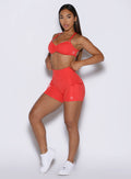 front left side profile view of a model adjusting the waistband wearing the PocketBoost Shorts in command red color