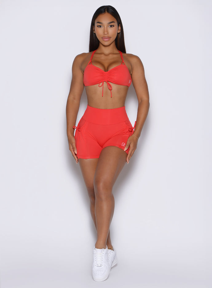 front profile view of a model resting both her hands on her thighs wearing the PocketBoost Shorts in command red color