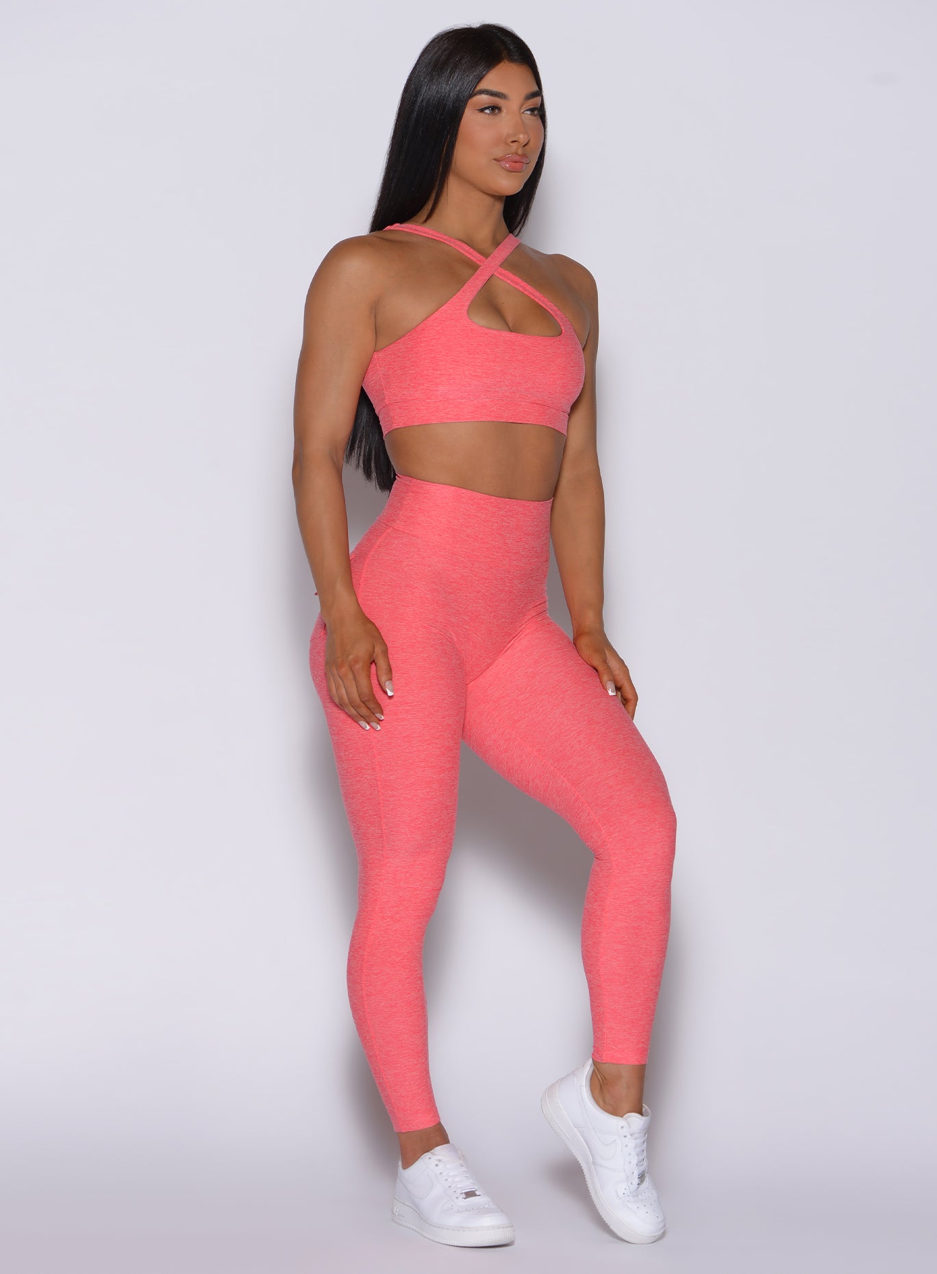 right side profile view of a model angled to her right wearing our Pocket Pop Leggings in papaya color and a matching bra