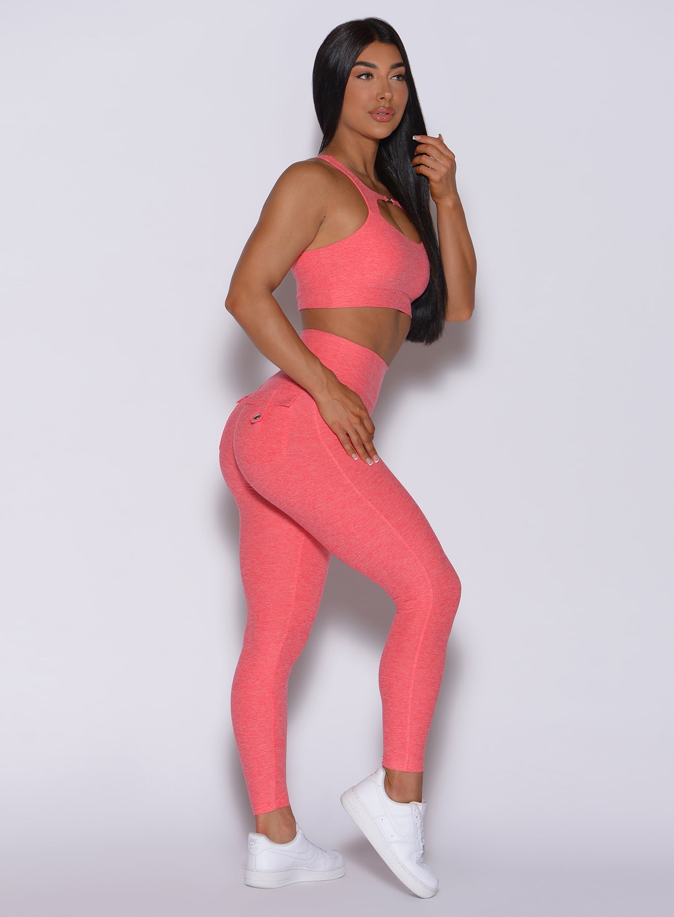 right side profile view of a model wearing our Pocket Pop Leggings in papaya color and a matching bra