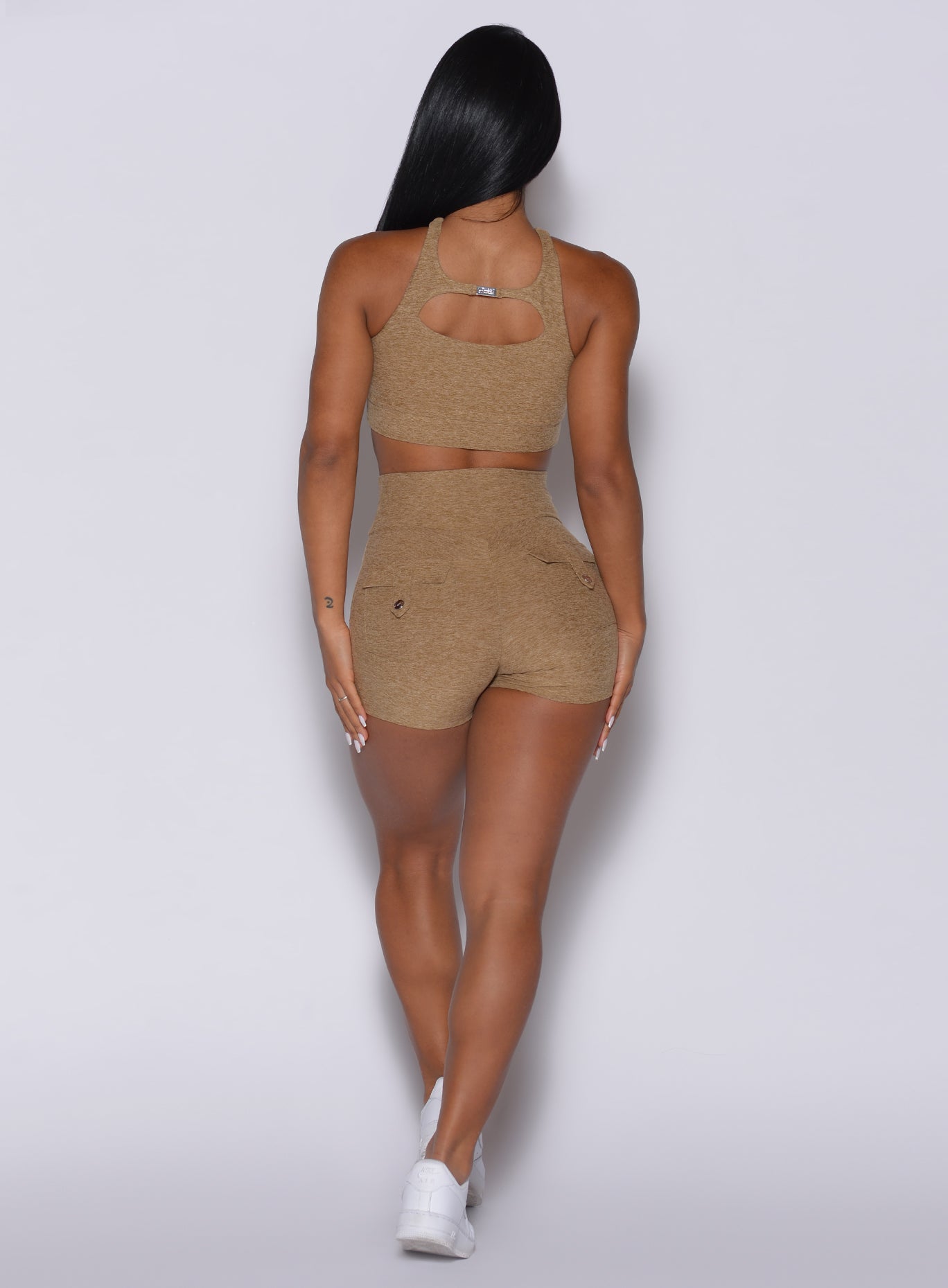 Back profile view of a model wearing our Pocket Pop Shorts and a sports bra in caramel color 