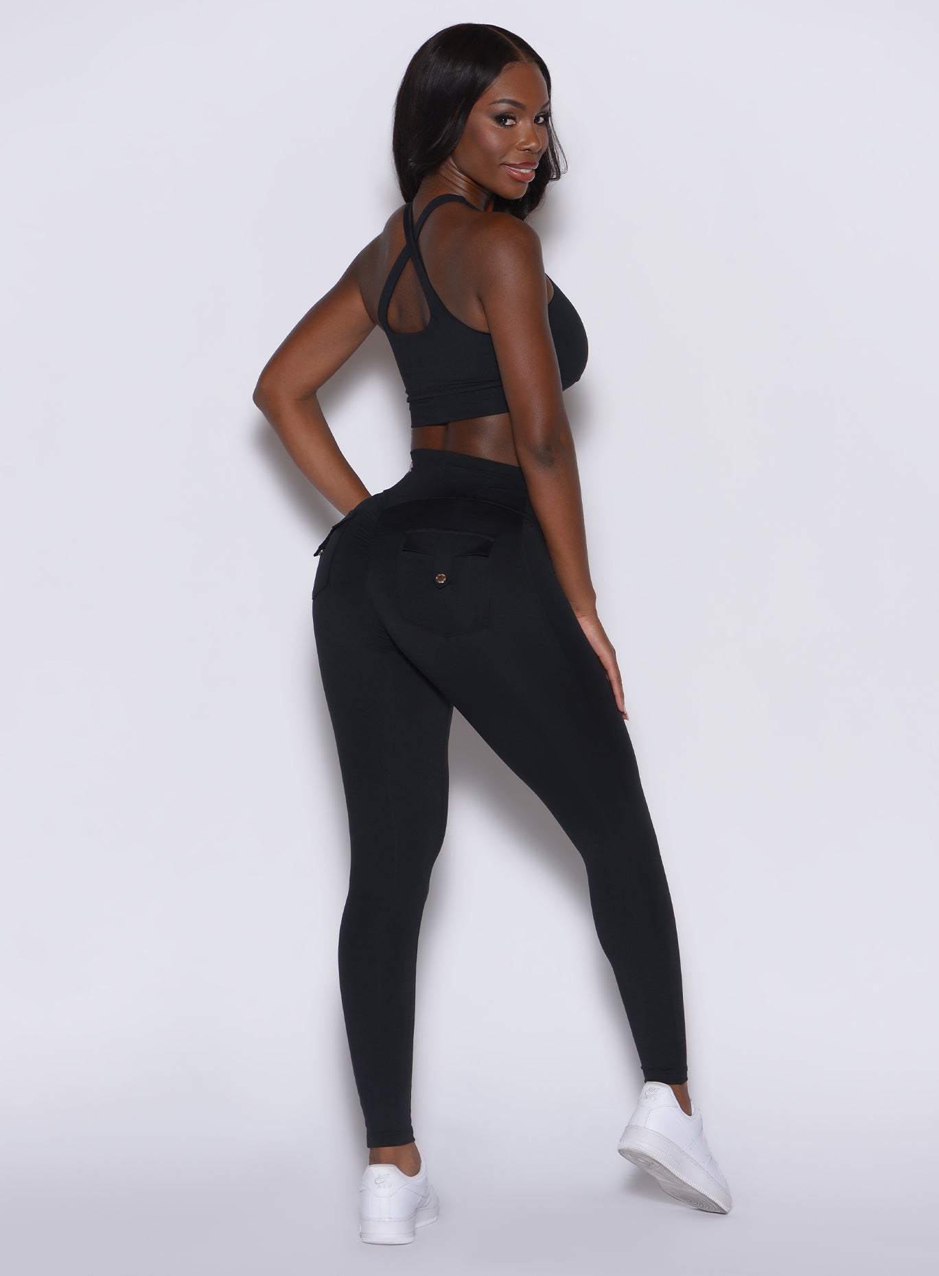 Right side profile view of a model wearing our black pocket pop leggings along with the matching bra