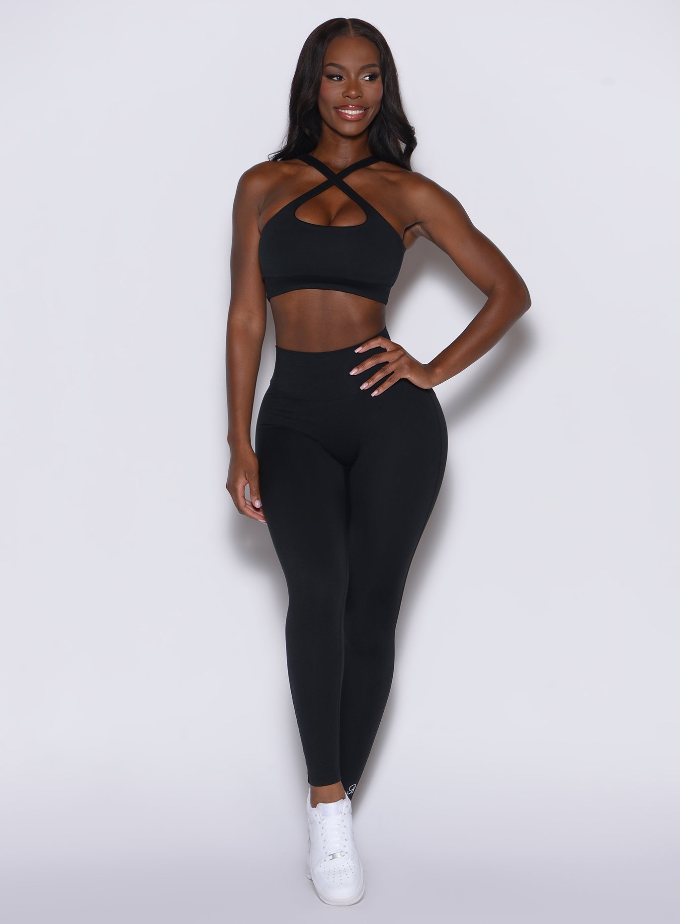 Front profile view of a model wearing our black pocket pop leggings along with the matching sports bra