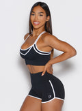 left side profile view of a model with both hands on her waist wearing the Power Line Bra in black color