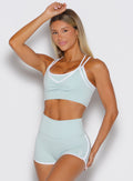 front view of a model with one hand resting on top of her head wearing the Power Line Bra in cool arctic color