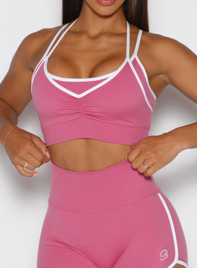 close up front view of a model with both hands on the waistband of the shorts wearing the Power Line Bra in empowered pink color