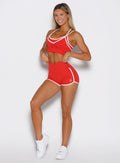 front profile view of a model with both hands on the waistband wearing the Power line shorts in power red color