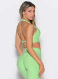 right side profile view of a model looking over her shoulder wearing the Power Zip Tank bra in electric green color