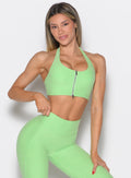 front profile view of a model with one hand on the waist wearing the Power Zip Tank bra in electric green color