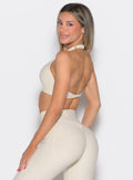 left side profile view of a model looking over her shoulder wearing the Power Zip Tank bra in pearl white color
