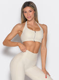 front profile view of a model with one hand on her waist wearing the Power Zip Tank bra in pearl white color