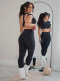 back profile view of a model looking over her shoulder in indoors wearing the Core Strength Tee in Heathered Black color