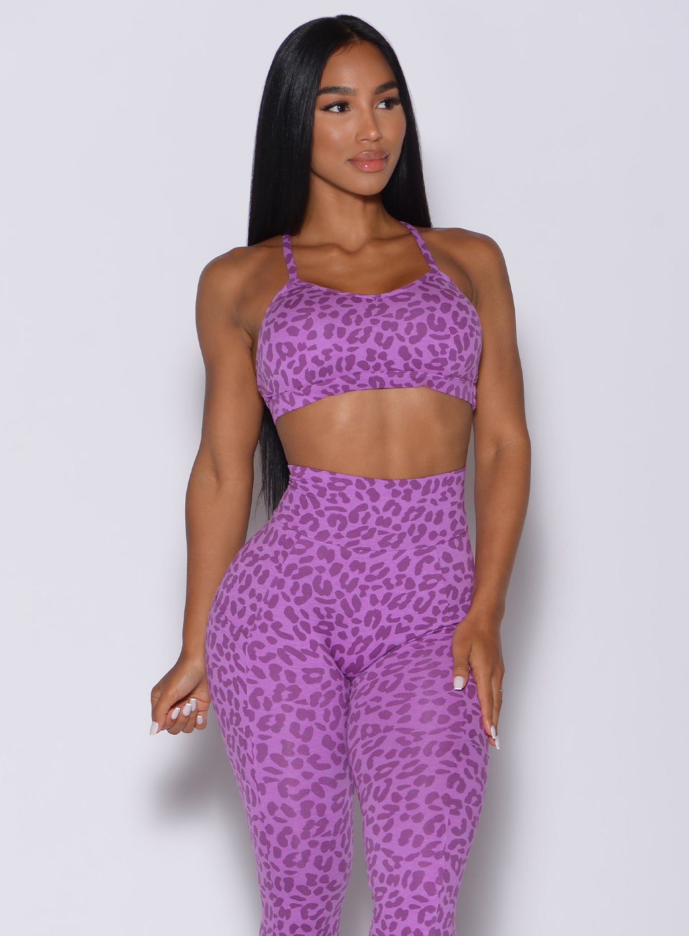 Front profile view of a model in our pumped sports bra in purple cheetah color and matching leggings