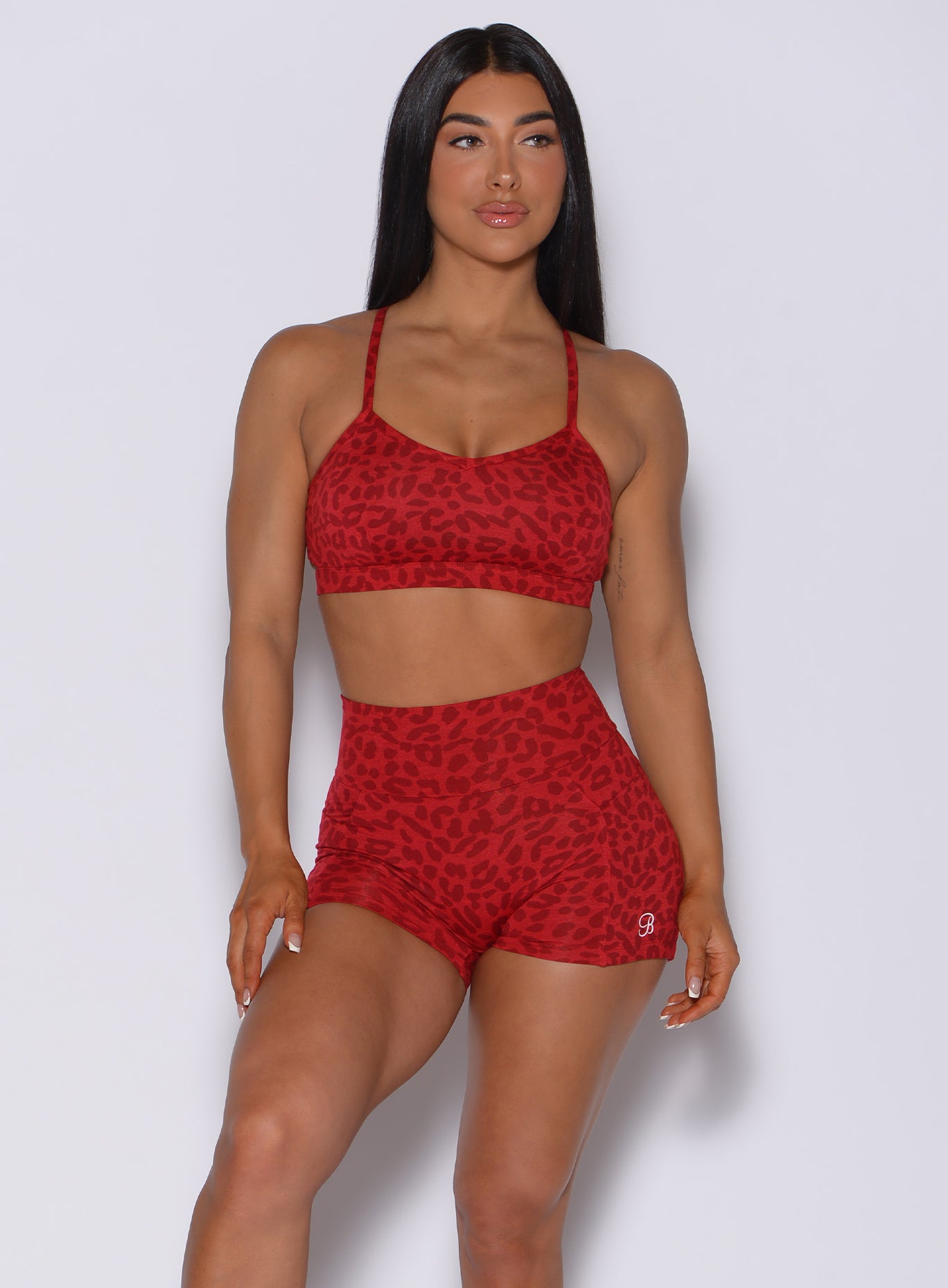 Front profile view of a model in our pumped sports bra in red cheetah color and matching shorts