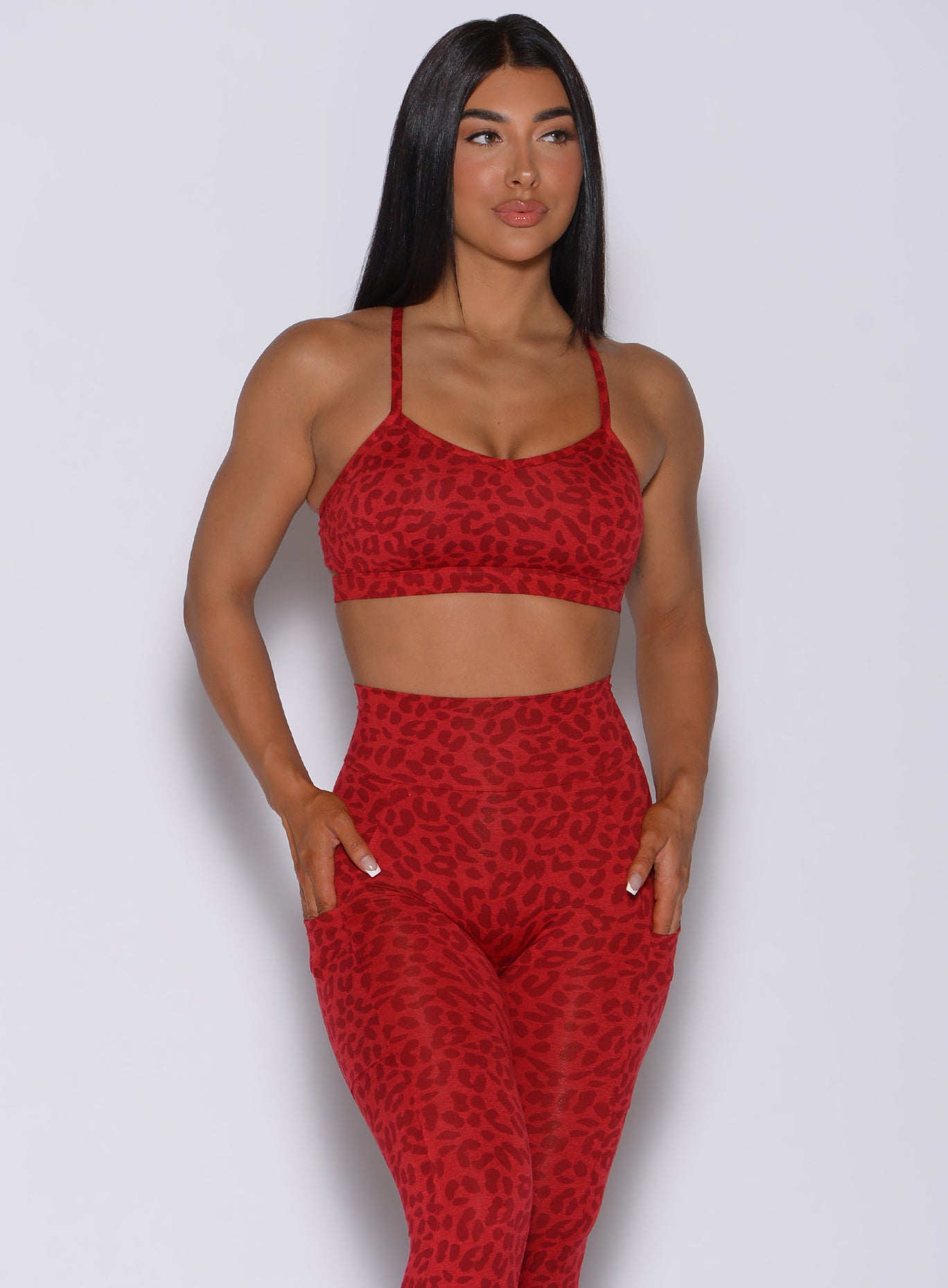 Front profile view of a model in our pumped sports bra in red cheetah color and matching leggings