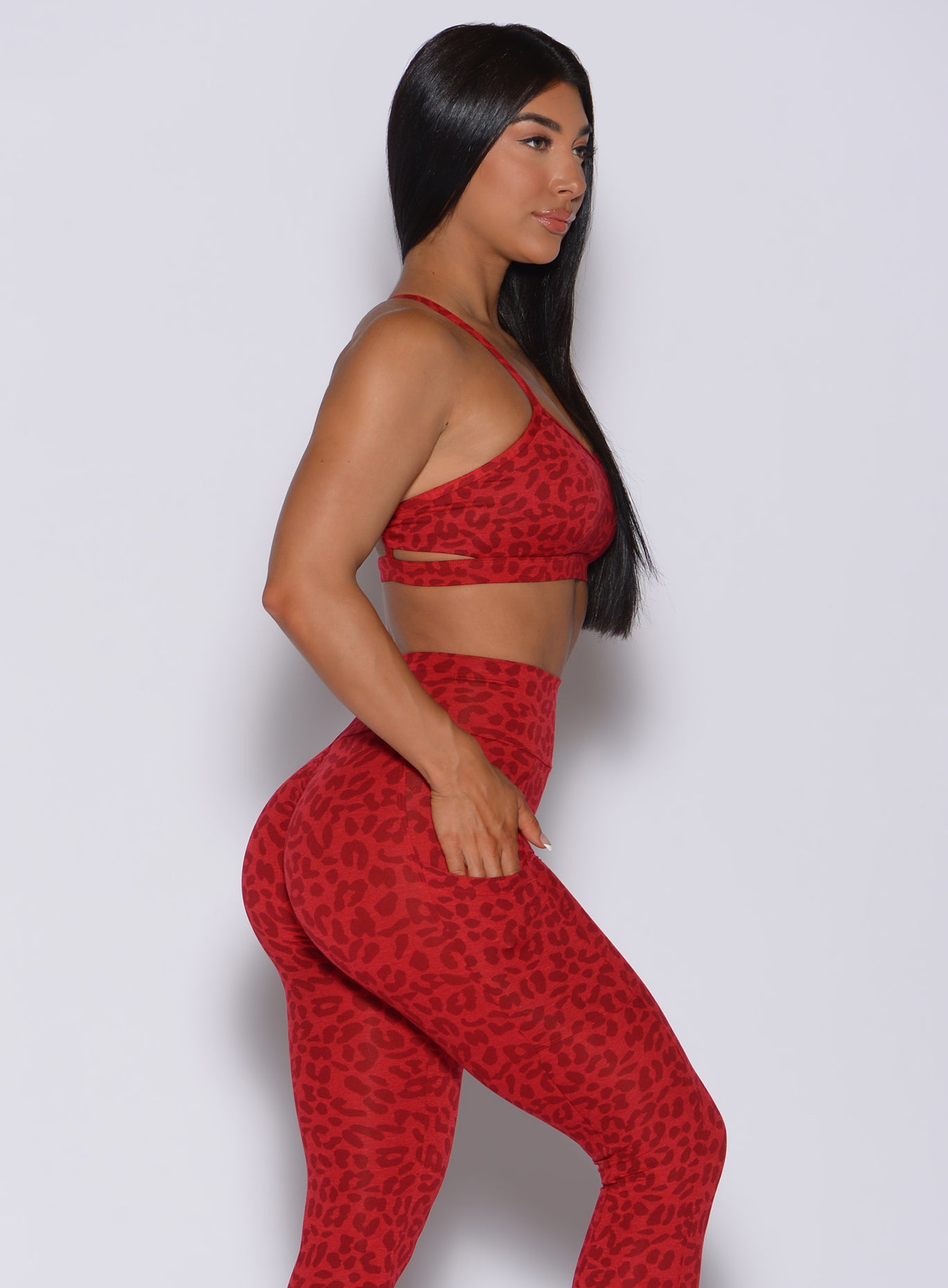Right side profile view of a model in our pumped sports bra in red cheetah color and matching leggings