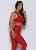 Right profile view of a model wearing our pumped sports bra in red cheetah color and matching leggings