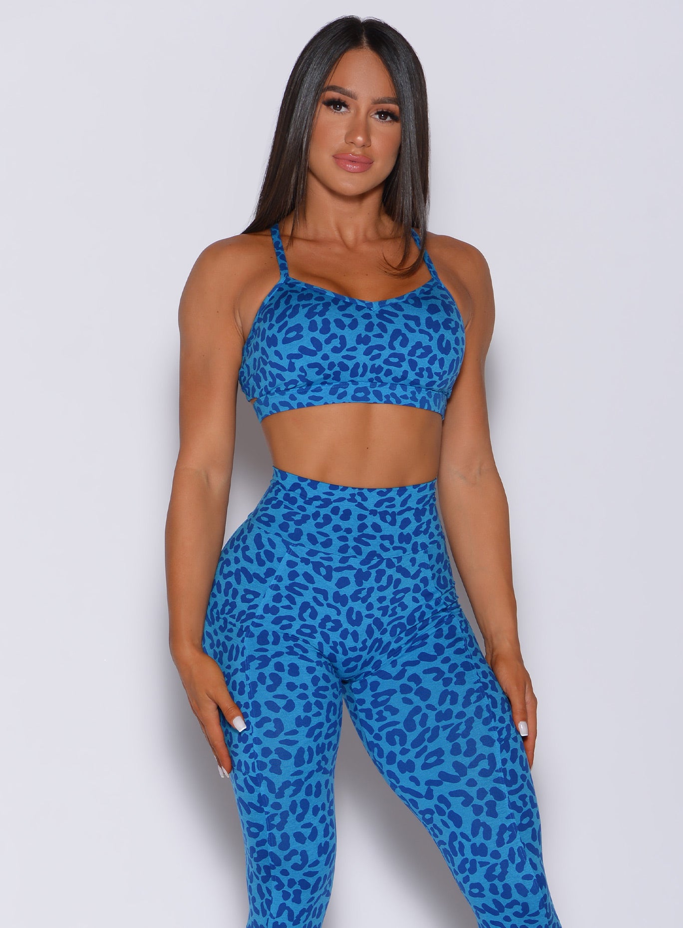 Model facing forward wearing our pumped sports bra in blue cheetah color and matching leggings