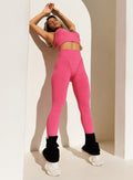 model leaning backward on a wall in outdoors wearing the Hardbody Leggings in Neon Flame color