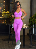beautiful model standing outside a coffee shop wearing the hardbody leggings and electric era top in purple rain with gray leg warmers