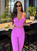 model in indoors with glasses on and holding drinks wearing the Hardbody Leggings in Purple Rain color