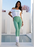 model standing near a swimming pool wearing the Star Power Tee in white color along with the hardbody leggings in sage color