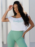 front view of a model in outdoors wearing the Star Power Tee in white color along with the hardbody leggings in Sage color