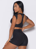 back left side profile view of a model with one hand on her waist wearing the Core Strength Tee in Heathered Black color