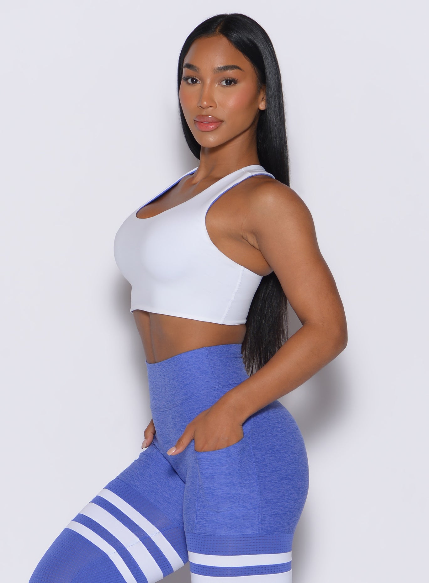 Left side profile view of a model wearing our white reversible tank bra along with a matching leggings