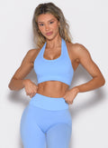 front profile view of a model with both hands on the waistband of the leggings wearing the Rib Backless Bra in vista blue color