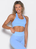 front profile view of a model with one hand on the waistband of the leggings wearing the Rib Backless Bra in vista blue color